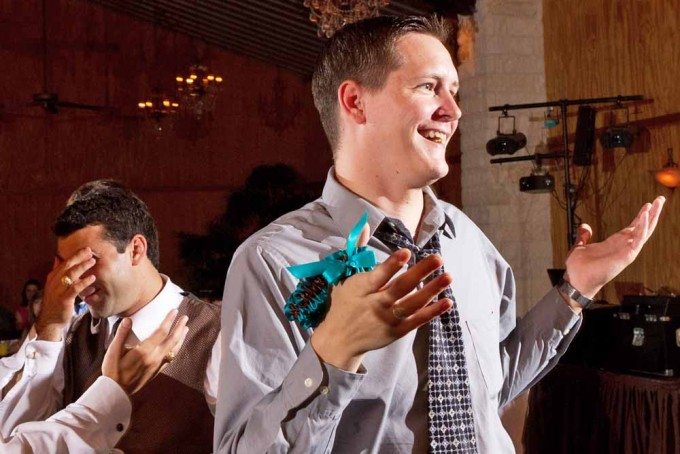 A man celebrates catching a wedding garter while another man looks dejected after missing it. 