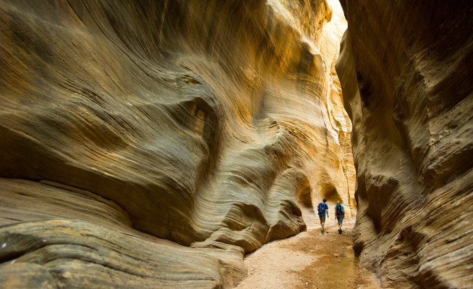 Man and woman hiking in slot canyon, Cannonville, Utah.