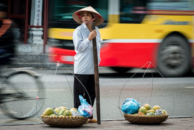 A fruit vendor sells her produce on the busy streets of Hanoi, V