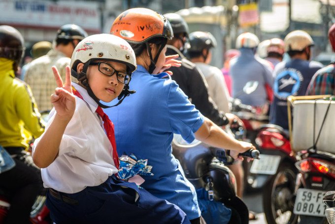 A young student on her way to school by motorbike, in Ho Chi Min