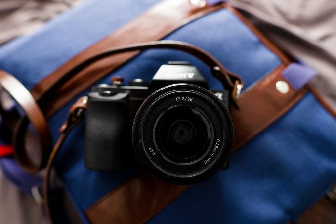 A Sony camera with a lens rests on a blue and brown bag.