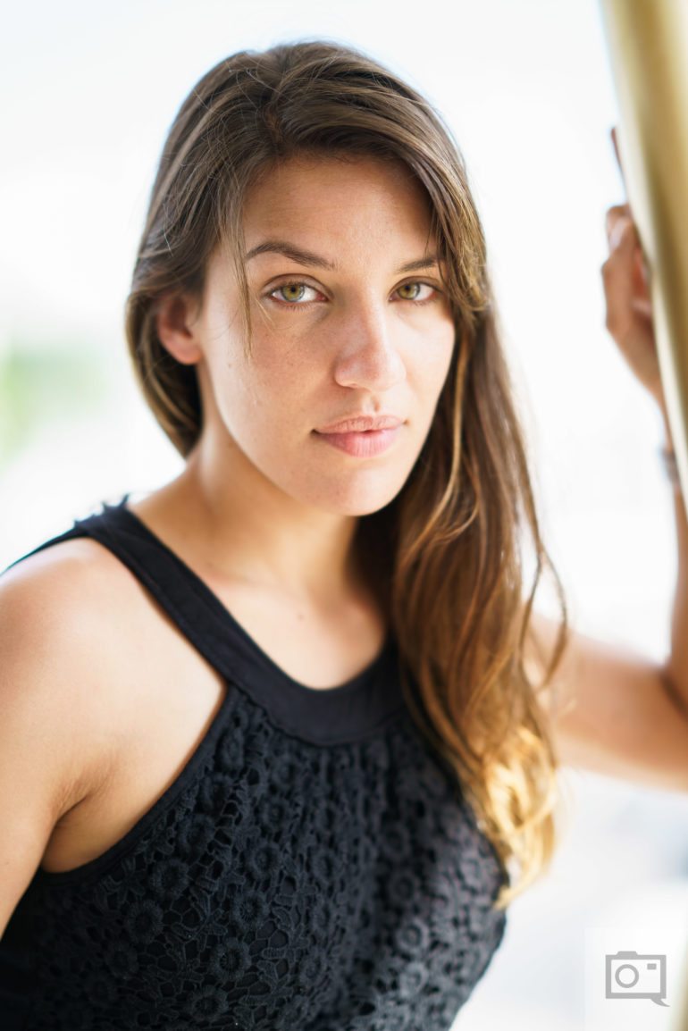 Woman with long brown hair in a black sleeveless top looking at the camera with a neutral expression.