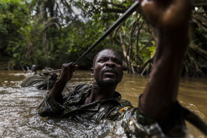 MBOKI, CENTRAL AFRICAN REPUBLIC, 25 NOVEMBER 2014: Ugandan soldiers cross one of many rivers while on patrol against the Lord's Resistance Army close to the border of the DRC. The Ugandan contingent based in CAR are focused on the aprehension of the Lord's Resistance Army, LRA, the notorious rebel group led by Joseph Kony which has terrorized citizens of Uganda, C.A.R, South Sudan and the Democratic Republic of Congo for the last 4 decades. Soldiers are seen crossing a river, a technique they have perfected with ropes despite the fact that many of the men cannot swim. The LRA contingent they are hunting is coming from Garamba National Park where they have been hunting ivory, a task ordered by Joseph Kony and detailed in a commander’s diary that this Ugandan contingent captured in an ambush earlier in 2014. Defectors say that Joseph Kony, leader of the LRA, is increasingly reliant on ivory as a means of trade for weapons and supplies from their hosts the Sudanese Army.