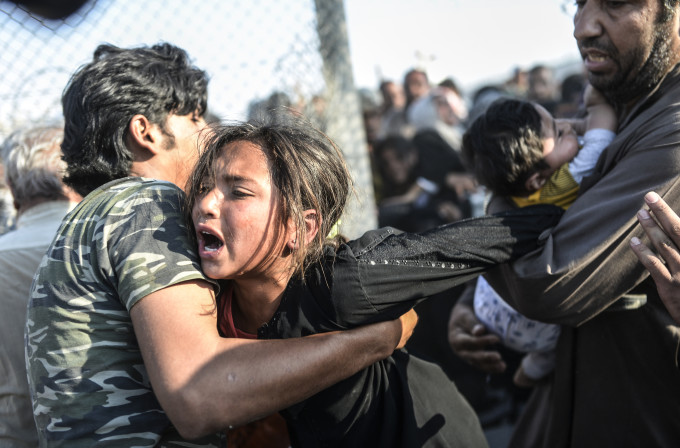 Syrians fleeing the war rush through broken down border fences to enter Turkish territory illegally, near the Turkish border crossing at Akcakale in Sanliurfa province on June 14, 2015. Turkey said it was taking measures to limit the flow of Syrian refugees onto its territory after an influx of thousands more over the last days due to fighting between Kurds and jihadists. Under an "open-door" policy, Turkey has taken in 1.8 million Syrian refugees since the conflict in Syria erupted in 2011. AFP PHOTO / BULENT KILIC / AFP / BULENT KILIC
