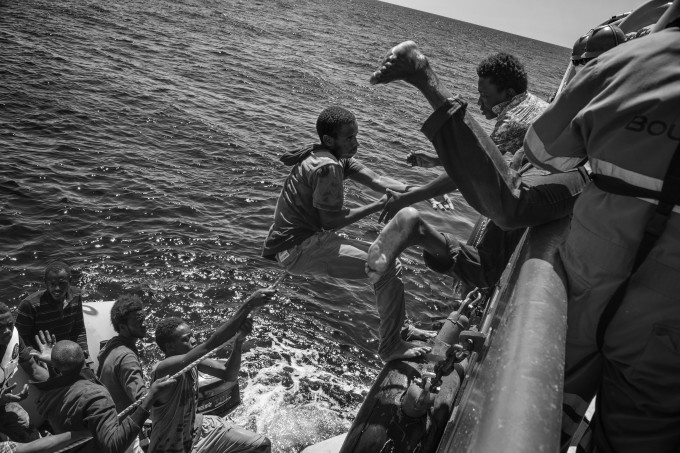 Some of the 95 migrants on board a sinking rubber dinghy frantically climb on board a rigid-hulled inflatable boat (RIB) launched to their rescue by the M.S.F. (Médecins Sans Frontières - Doctors Without Borders) Bourbon Argos search and rescue ship patrolling the Mediterranean Sea. 21 August 2015. In 2015 the ever-increasing number of migrants attempting to cross the Mediterranean Sea on unseaworthy vessels towards Europe led to an unprecedented crisis. Nearly 120 thousand people have reached Italy in the first 8 months of the year. While the European governments struggled to deal with the influx, the death toll in the Mediterranean reached record numbers. Early in May the international medical relief organization Médecins Sans Frontières (M.S.F.) joined in the search and rescue operations led in the Mediterranean Sea and launched three ships at different stages: the Phoenix (run by the Migrant Offshore Aid Station), the Bourbon Argos and Dignity.