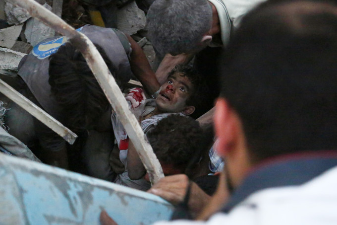 Syrians evacuate an injured boy from rubble following a reported air strike on a rebel-held town of Douma, northeast of the capital Damascus on June 16, 2015. Nearly every day, Syria's air force drops barrel bombs -- containers packed with crude explosives and shrapnel -- on areas wrested from government control by rebels. AFP PHOTO / SAMEER AL-DOUMY