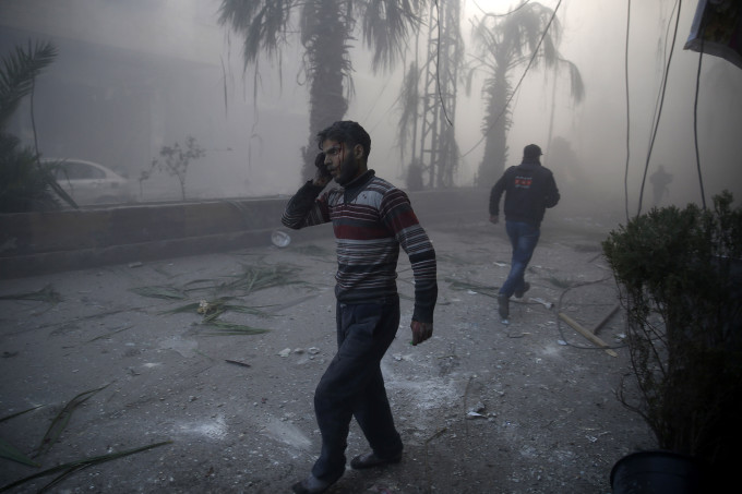 A wounded man walks out of a dust cloud following reported airstrikes in the town of Hamouria in the eastern Ghouta region, a rebel stronghold east of the Syrian capital Damascus, on December 9, 2015. The Syrian Observatory for Human Rights reported at least 11 civilians, including four children, were killed in strikes on the town of Hamouria, but said it was unclear if they were carried out by Russian or regime aircraft. AFP PHOTO / SAMEER AL-DOUMY