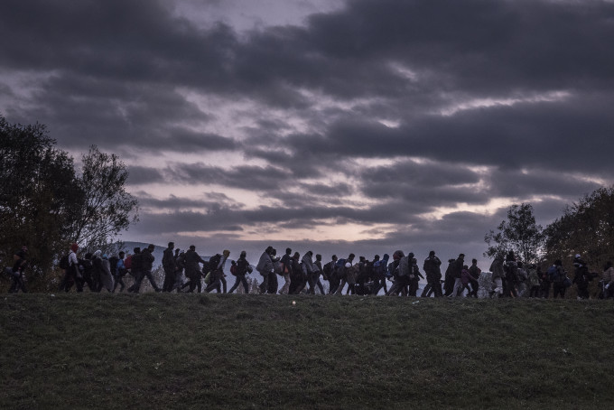 8 - Migrants walked atop a dike as Slovenian riot police escorted them to a registration camp outside Dobova. War, drought and more are driving millions of people from their homelands.