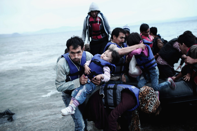 An Afghan refugee carries his child as he arrived on a beach on the Greek island of Kos, after crossing a part of the Aegean Sea between Turkey and Greece, on May 27, 2015.
