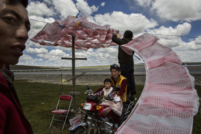 MADOU, CHINA - JULY 24:Tibetan nomads put up a string of Buddhist prayer flags near a government resettlement community on July 24, 2015 on the Tibetan Plateau in Madou County, Qinghai, China. Tibetan nomads face many challenges to their traditional way of life including political pressures, forced resettlement by China's government, climate change and rapid modernization. (Photo by Kevin Frayer/Getty Images)