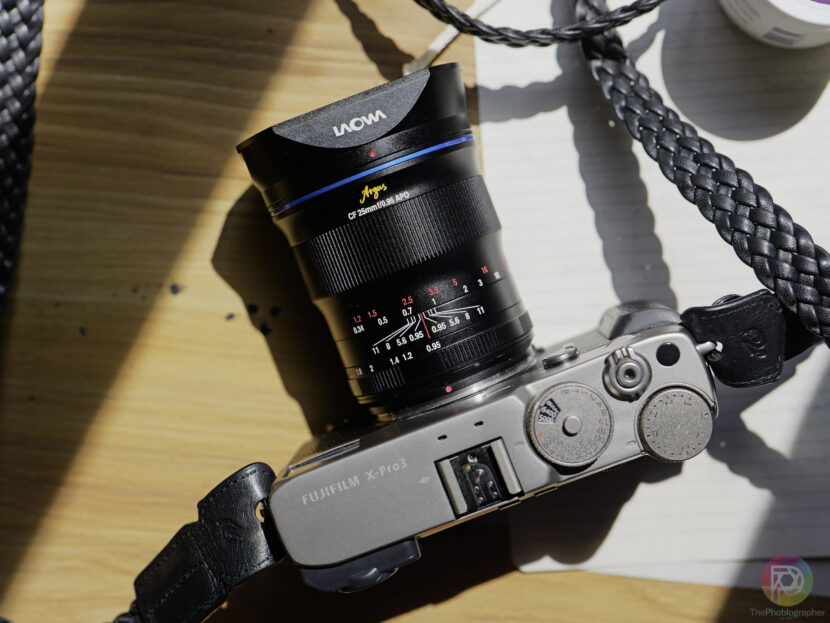 Laowa Showcases Four New Exciting Lenses at China P&E 2025 A Fujifilm X-Pro3 camera with a Laowa lens rests on a wooden surface in bright sunlight.