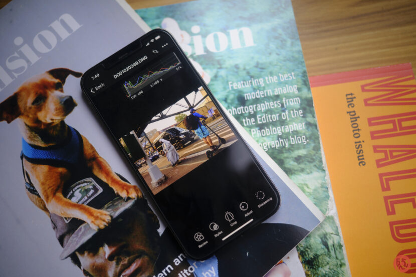 Capture One for iPhone Review: Does Adobe Do it Better? A smartphone editing a photo rests on magazines, one with a dog on the cover and another titled WHALED.