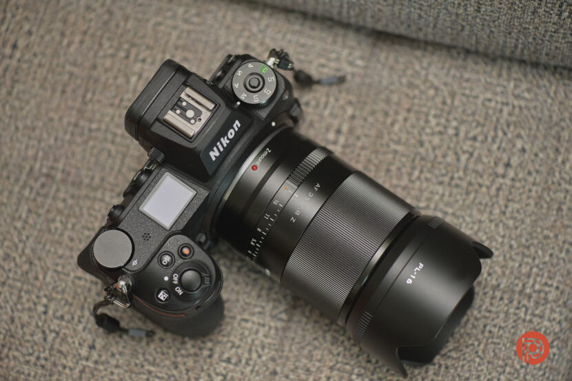 A Nikon camera with a large lens rests on a textured gray surface.