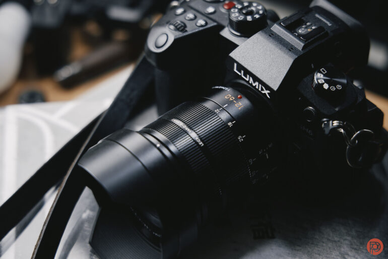 A close-up of a black Panasonic Lumix camera with a large lens, resting on a table.