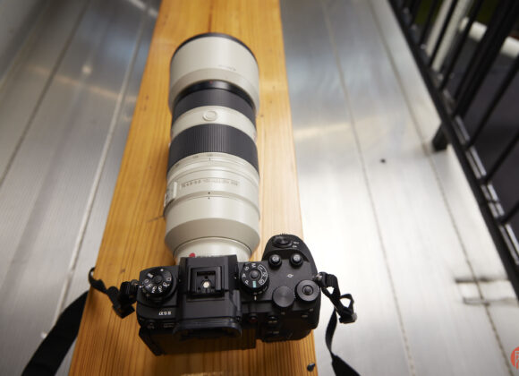 The Sony a9 III sits on top of a wooden bench.