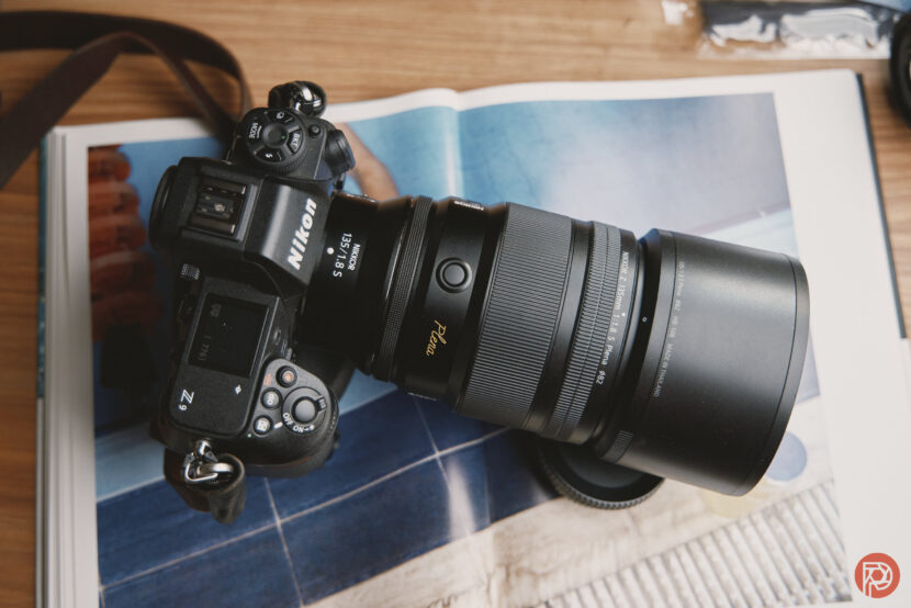A Nikon Z camera with a large lens rests on an open magazine showing a blue-toned photo.