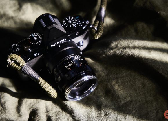 A Nikon Z5 camera with a lens and strap rests on a green fabric surface in sunlight.