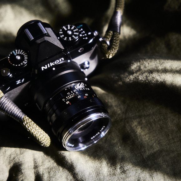 A Nikon Z5 camera with a lens and strap rests on a green fabric surface in sunlight.