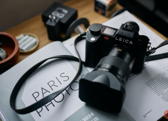 A Leica camera rests on an open magazine with the text PARIS PHOTO visible in bold letters.