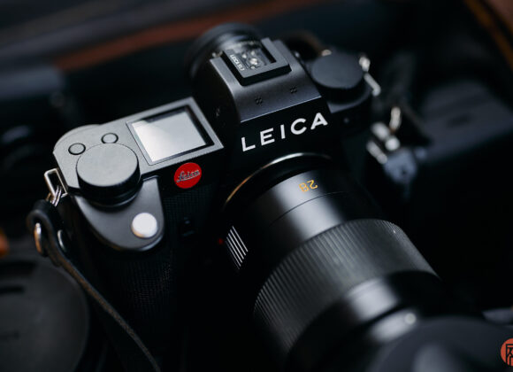 Close-up of a black Leica camera with a lens attached, showing the brand name and controls.