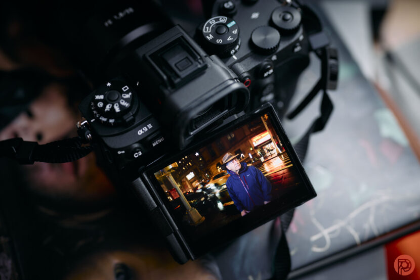 I Don't Think You Understand How Big the Latest Profoto Announcement Is A camera displays a photo of a man in a blue jacket standing on a city street at night.