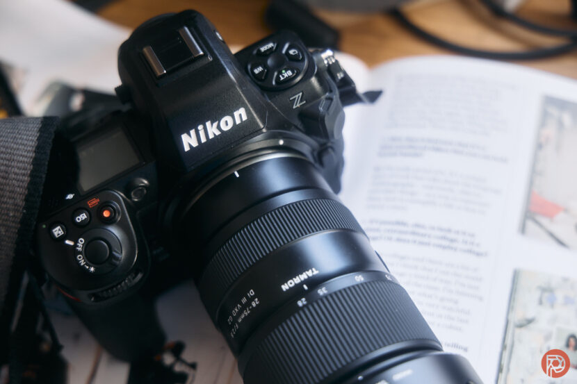 A Nikon camera with a Tamron lens rests on an open magazine page.