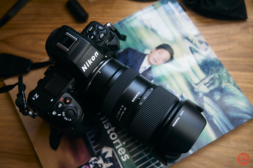 I’m a Nikon Fanboy – Clearly, I Don’t Mind Blurry Photos A Nikon camera with a Sigma lens rests on a magazine atop a wooden surface.
