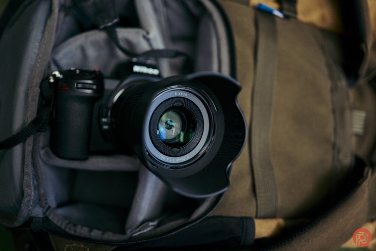 Close-up of a camera with a large lens packed inside an open camera bag.