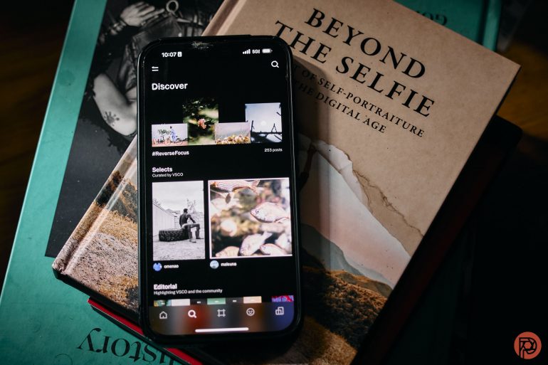 Smartphone displaying a photography app on a stack of photography books.