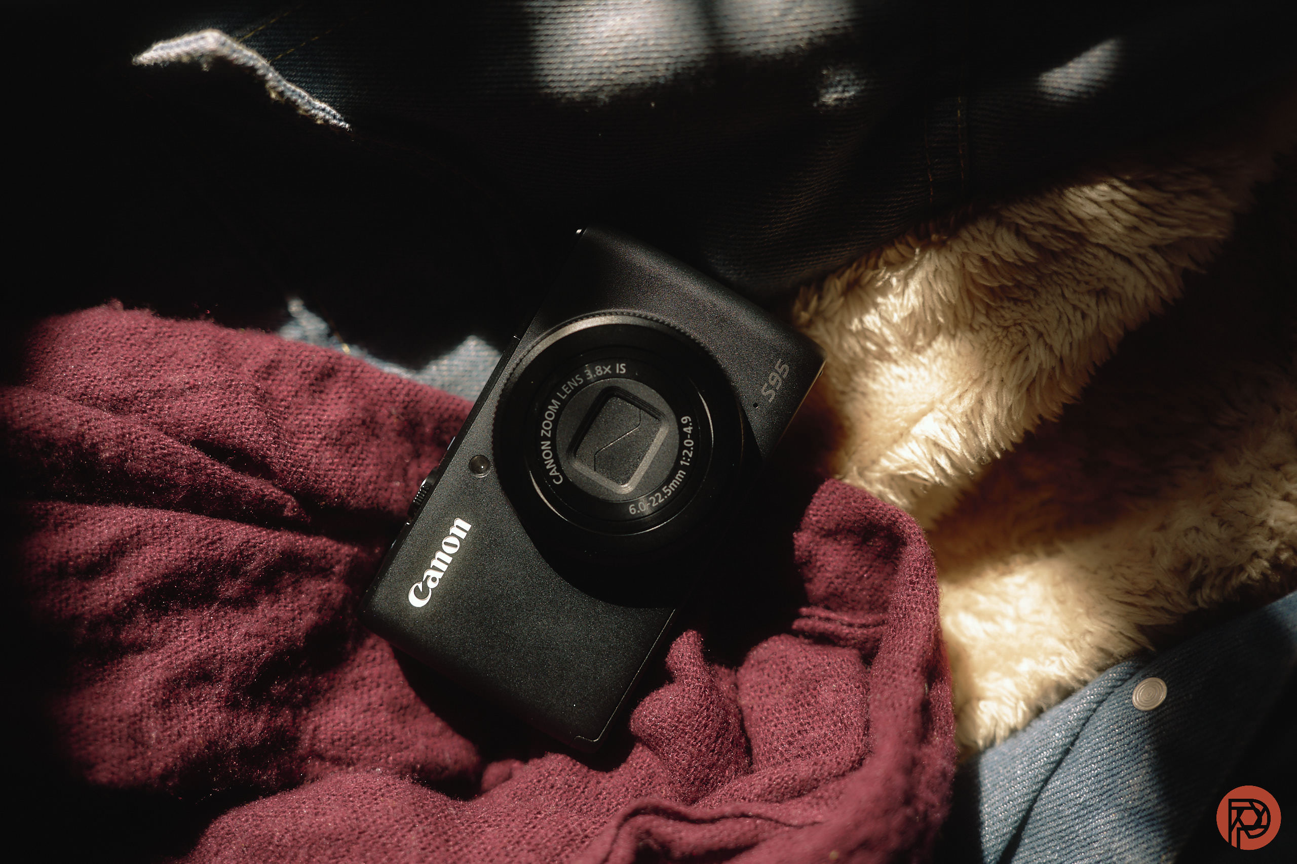 Canon camera placed on a bed of soft fabrics in warm, dappled light.