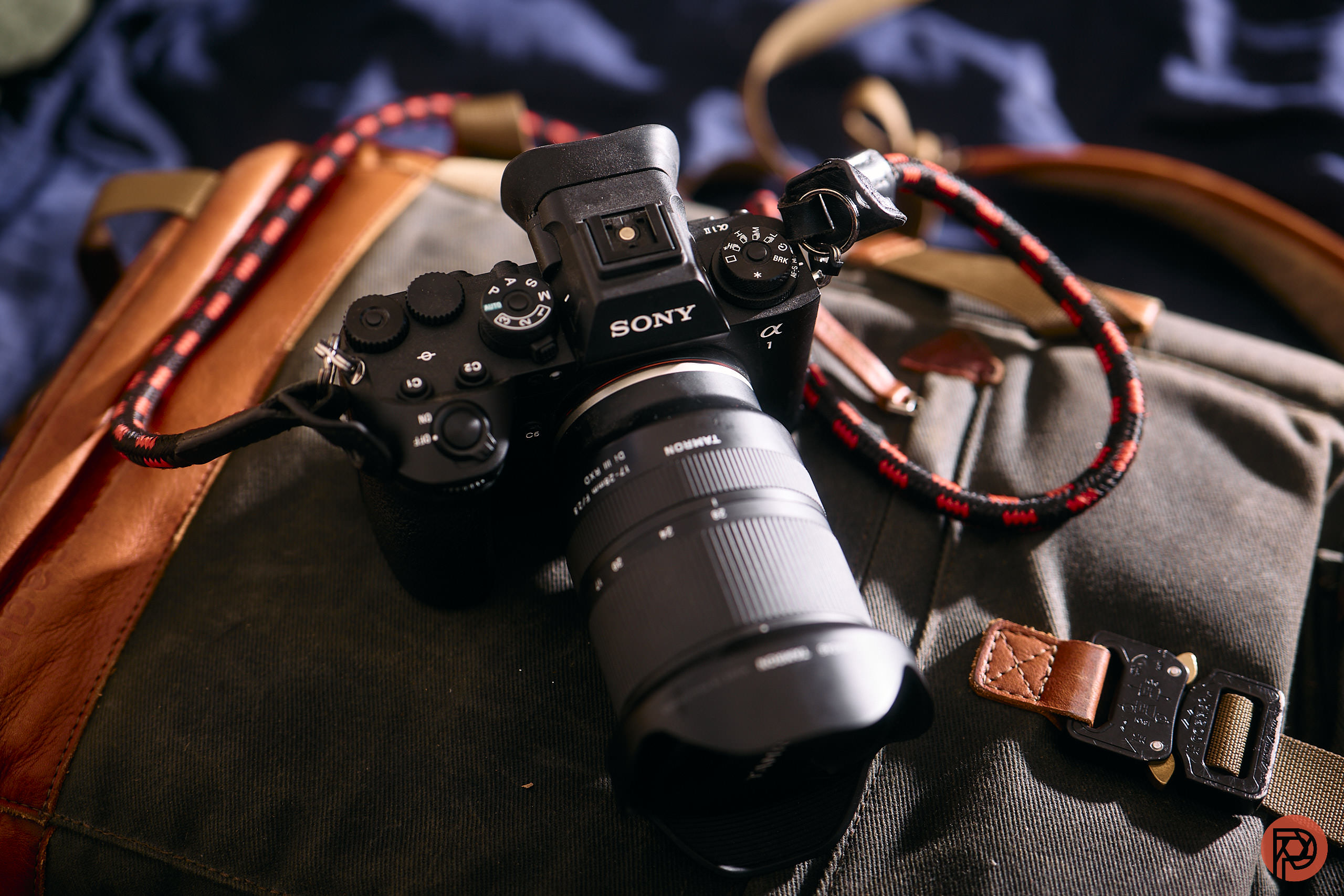 Why You Don't Need the Most Expensive Camera A Sony camera with a large lens rests on a canvas and leather bag in natural light.