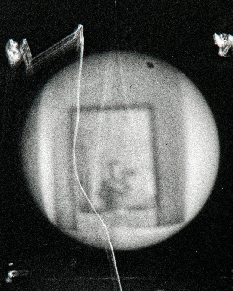 A blurry black and white image crafted through DIY cameras showcases abstract shapes with a circular focus area in the center.