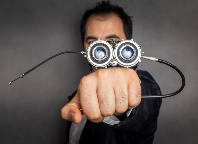 A person proudly holds a large, steampunk-style device with circular lenses aimed directly at the camera, a remarkable DIY camera creation that blends artistry and innovation.