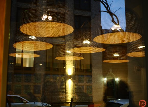 Reflection of basket-style hanging lights on a glass window with an urban street scene in the background.
