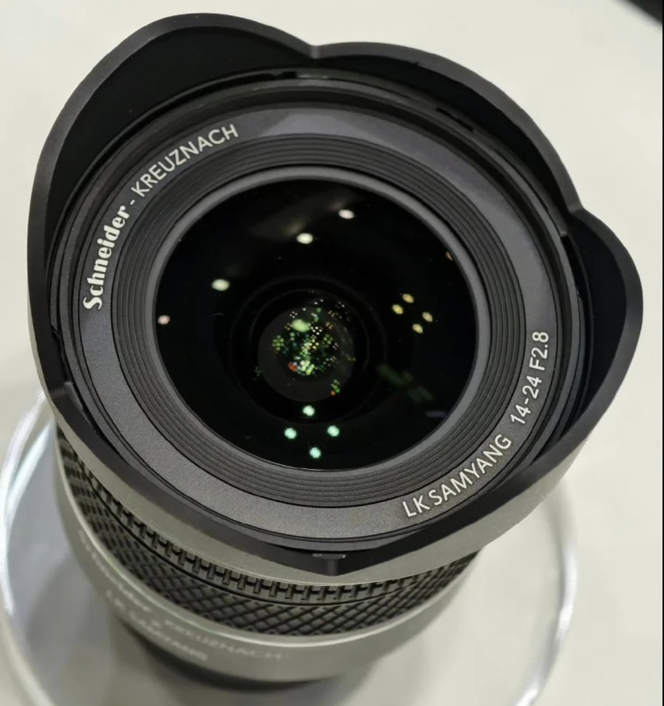 Close-up of a Schneider-Kreuznach LK Sanyang 14-24mm f/2.8 camera lens with reflections on the glass.