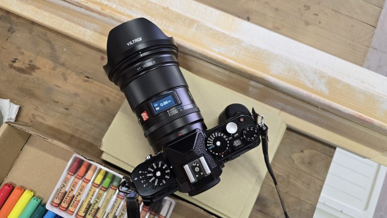 Camera with Viltrox lens on a wooden surface, surrounded by colored markers.