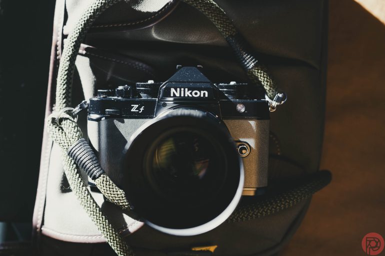 A Nikon Z fc camera with a large lens sits partially in a bag, with light and shadows on it.