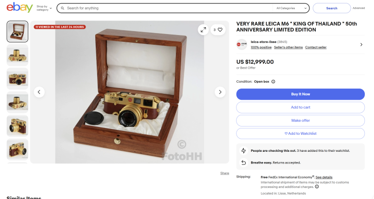 Gold Leica camera with lens in a wooden display box, shown on an eBay listing page for a limited edition model.