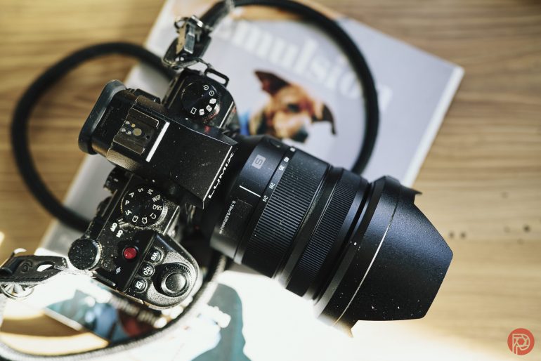 Close-up of a black DSLR camera with a lens, resting on a book with a dog on the cover.