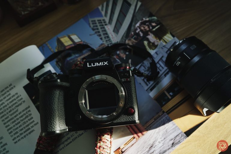 A Lumix S1 camera body and a detached lens rest on an open magazine in sunlight.