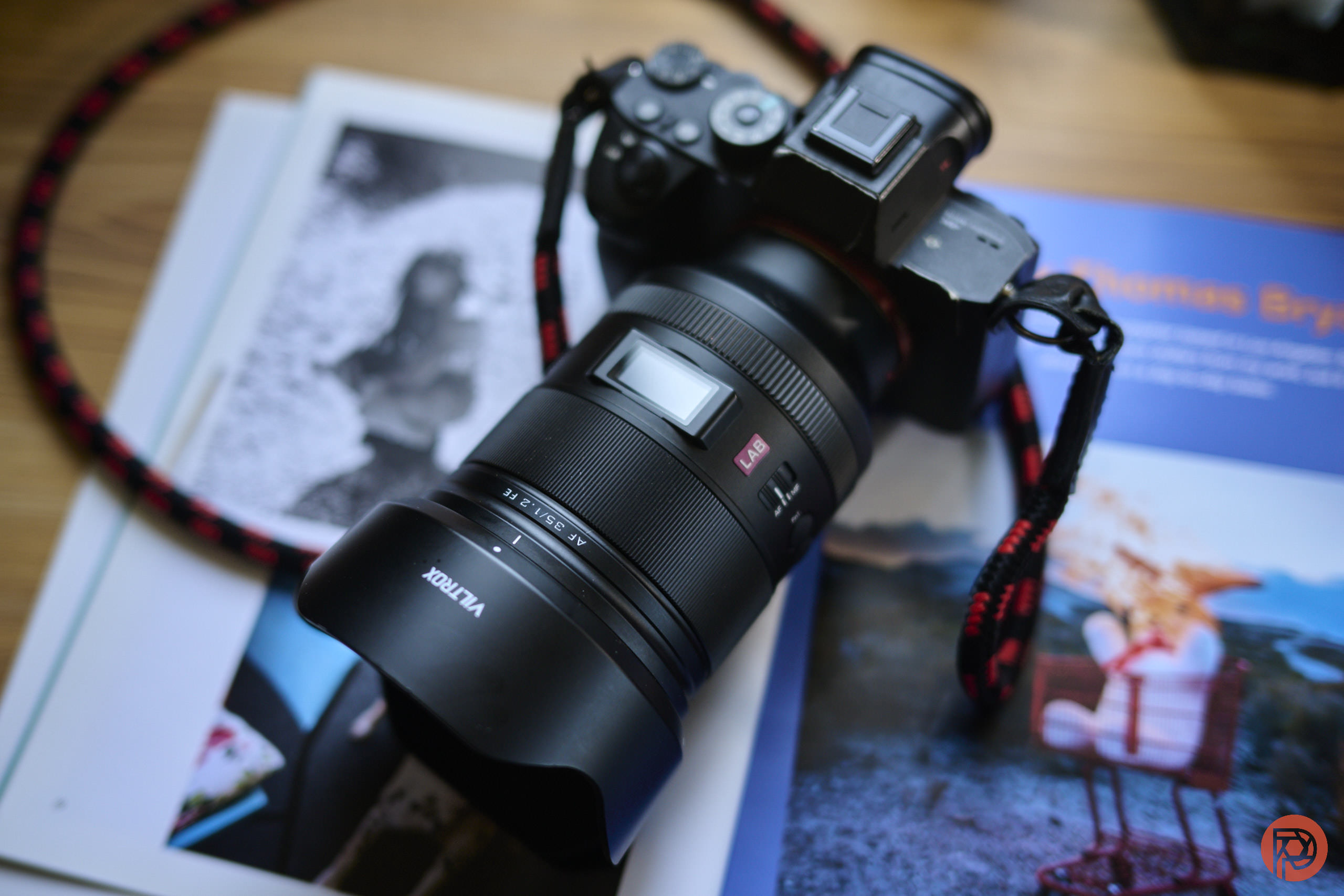 A black camera with a large lens rests on an open magazine with colorful images and text.