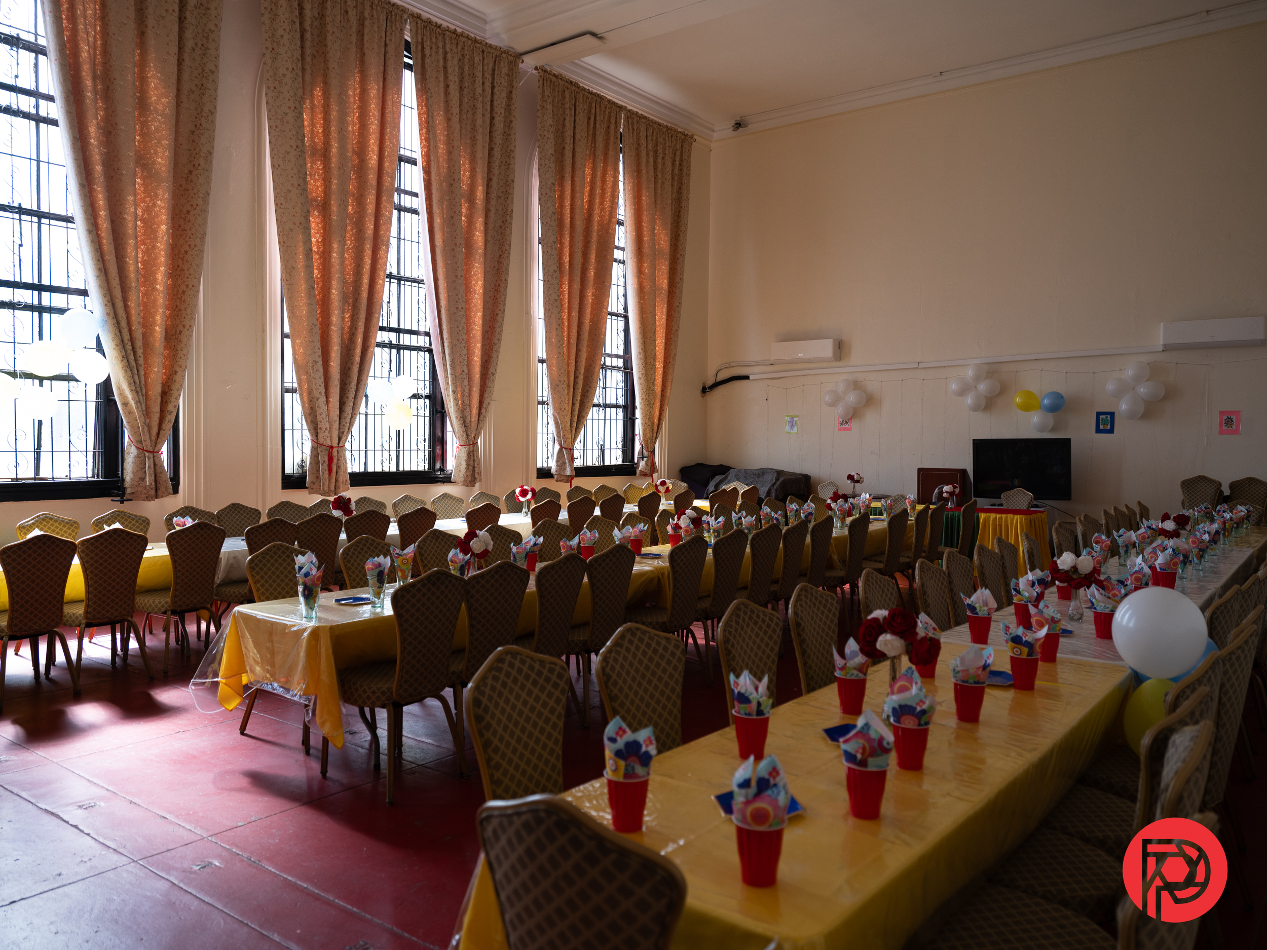How Gen Z is Rewriting the Rules of Photography Long tables with yellow tablecloths and party favors in a decorated room with large windows and curtains.