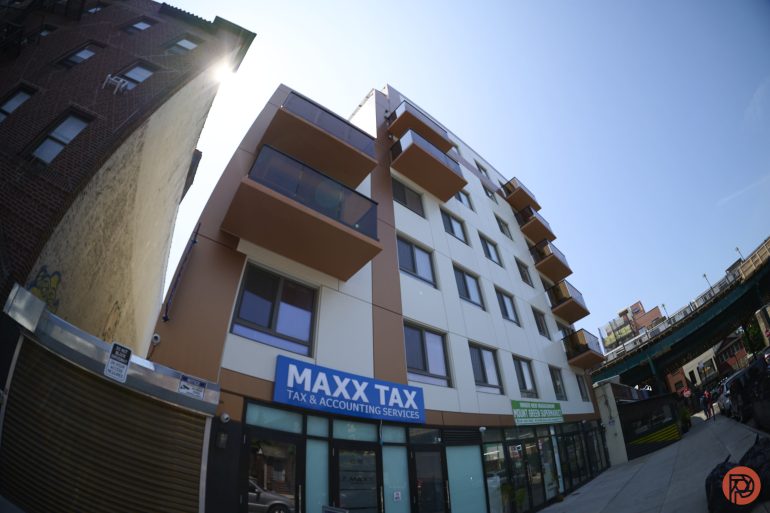 Wide-angle view of a modern building with MAXX TAX office on the ground floor under a clear blue sky.