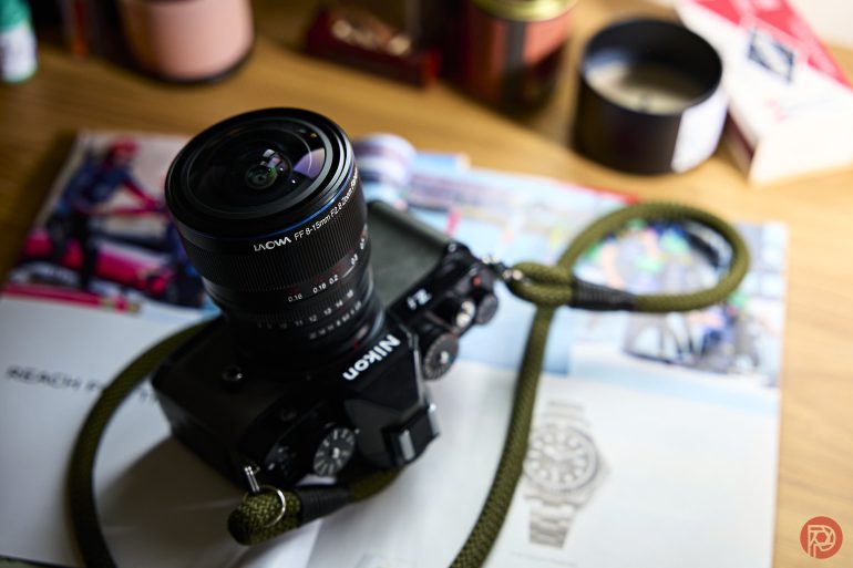 A Nikon camera with a green strap rests on an open magazine on a wooden surface.