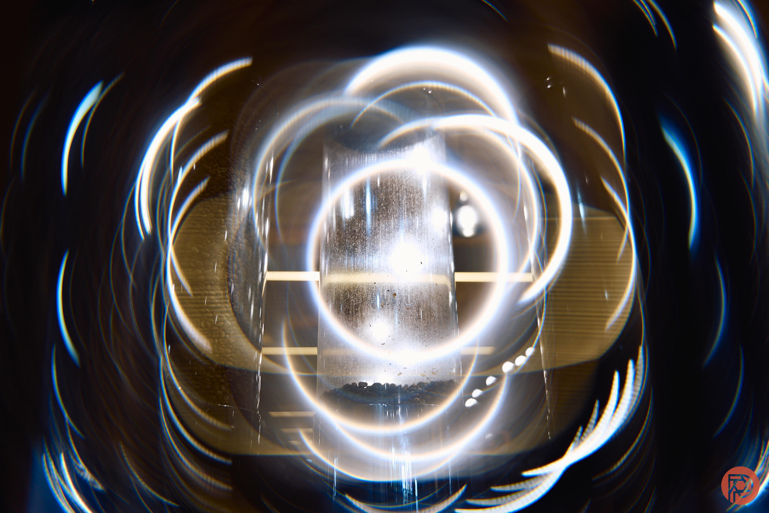 Are We Overthinking Photography? Abstract image of swirling white light rings with a bright central vertical glow and a dark background.