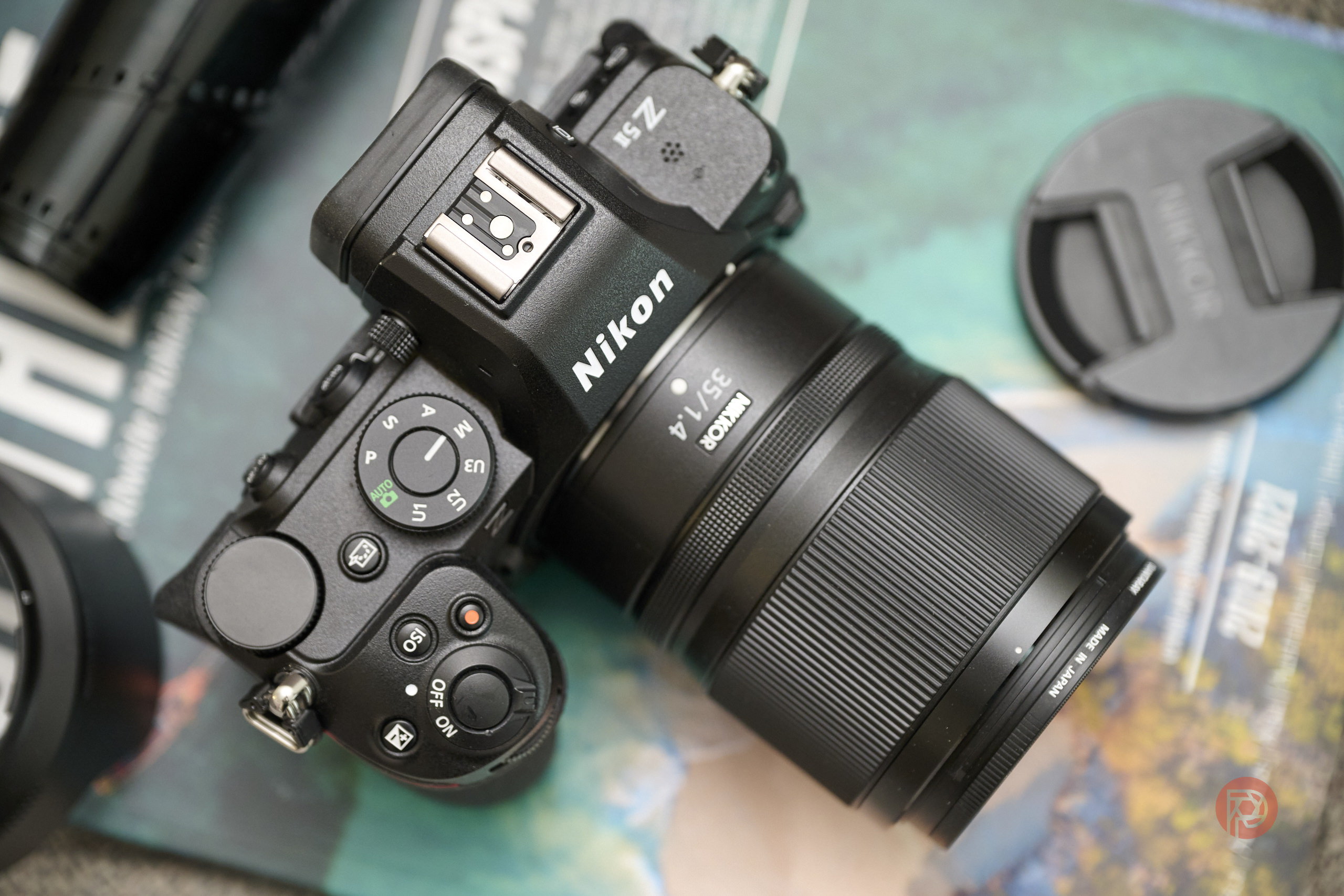 A Nikon Z5 II camera with a 35mm lens rests on a magazine next to a lens cap.