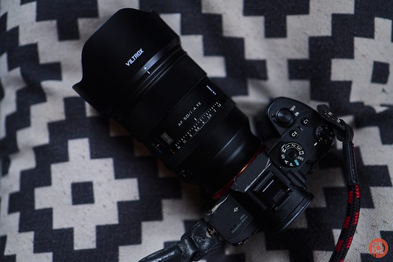 A Viltrox camera with a large lens rests on a patterned black-and-white cushion.