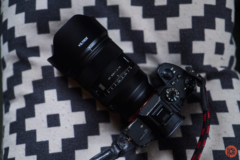 A Viltrox camera with a large lens rests on a black and white patterned pillow.