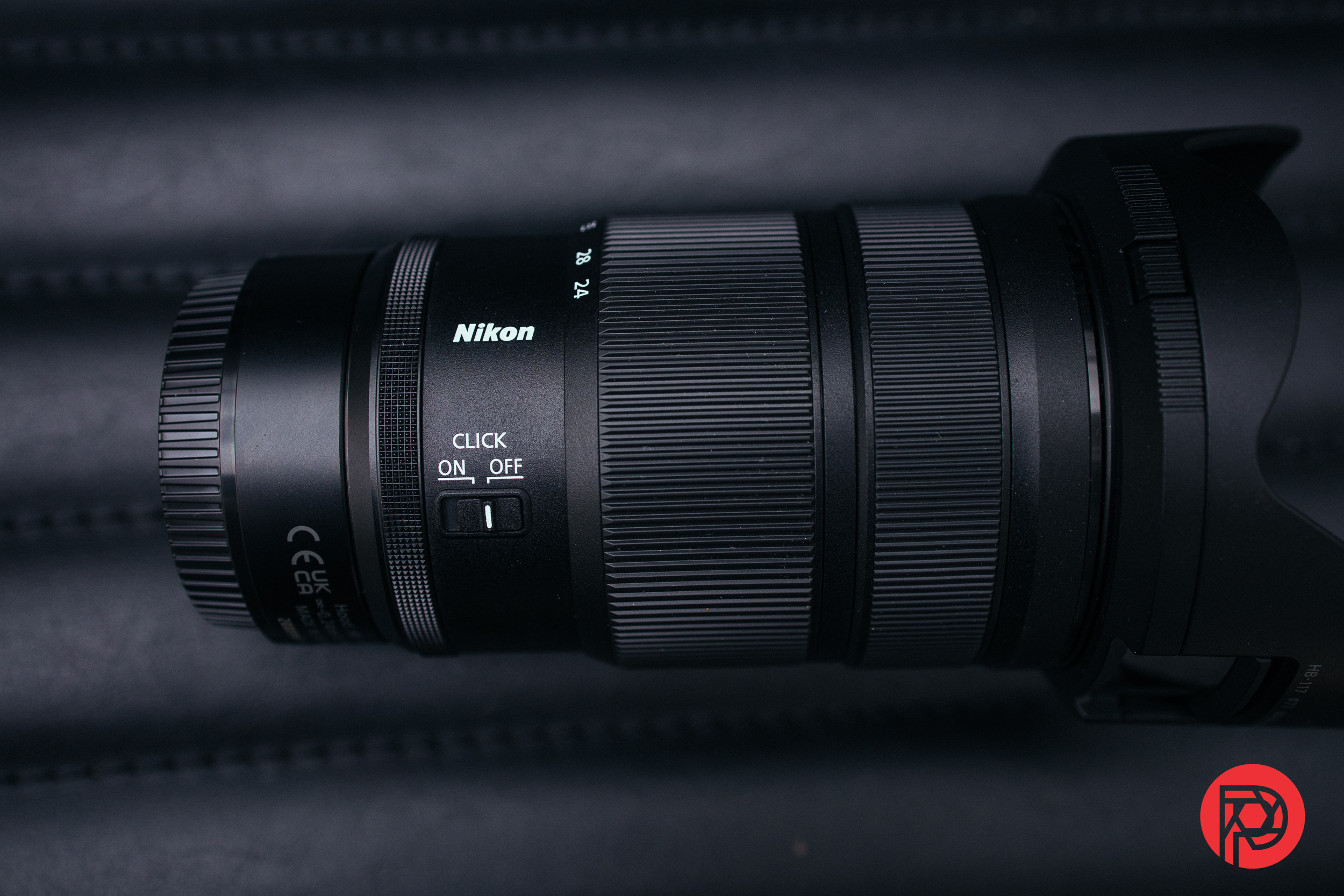 A Nikon camera lens with focus and zoom rings, shown on a dark background.