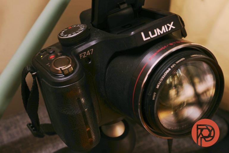 A close-up of a black Lumix FZ47 camera with a large lens and a red logo in the corner.